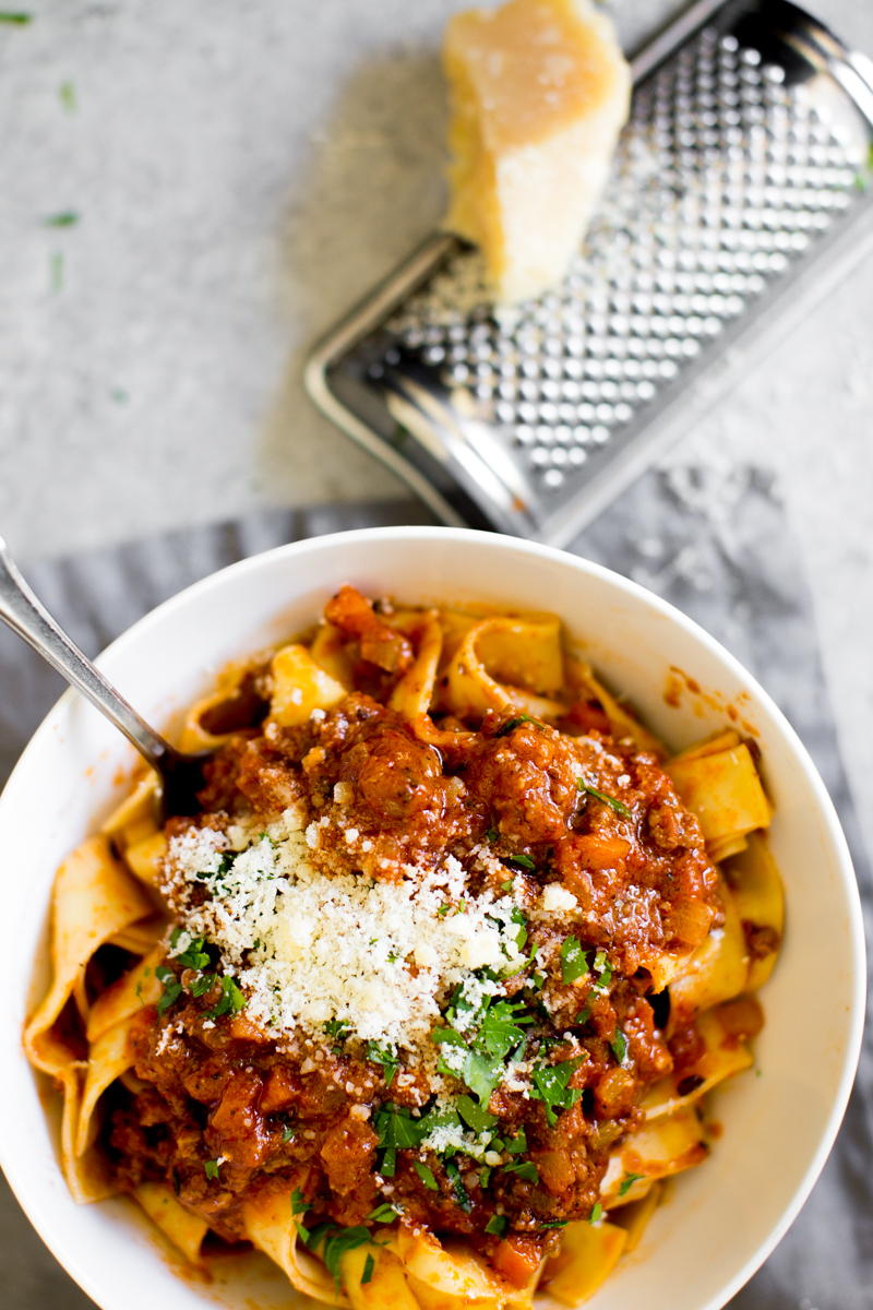 Instant Pot Bolognese sauce over pasta in a bowl with cheese and parsley for garnish