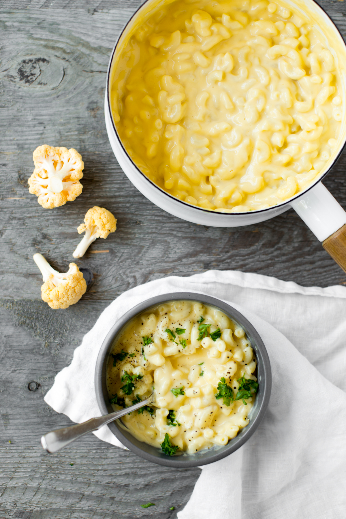 bowl of stovetop cauliflower mac and cheese with parsley and gray background