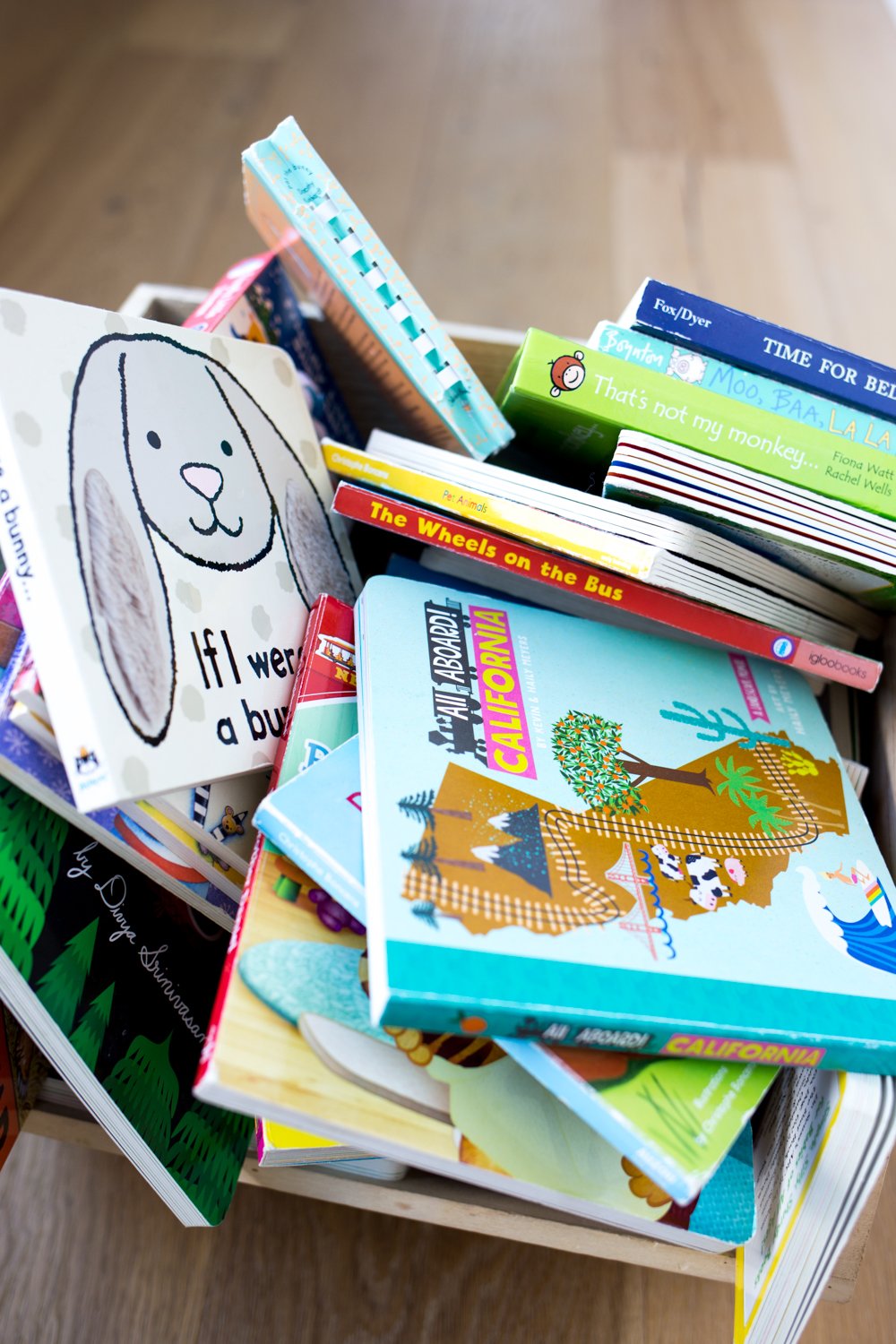 Pile of children's books in a wooden bin