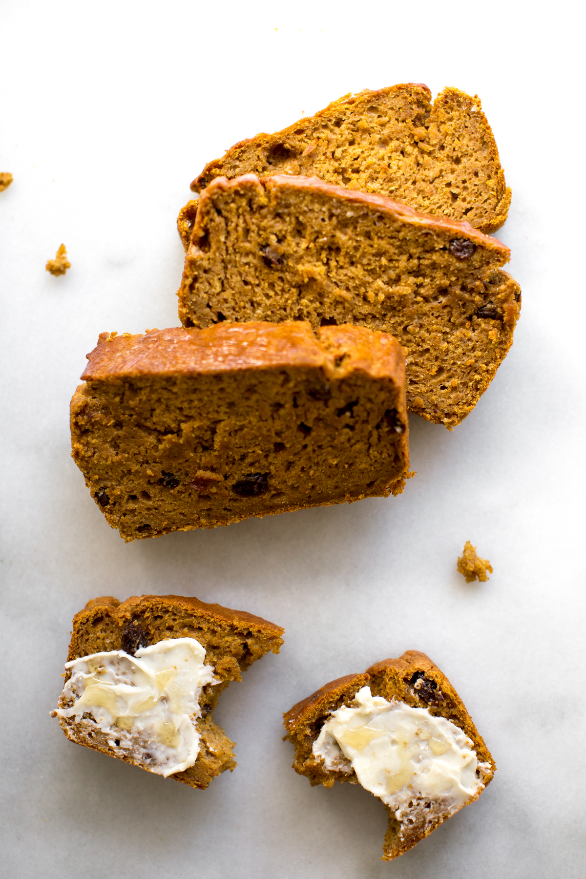 Slices of pumpkin bread smeared with butter and a drizzle of honey