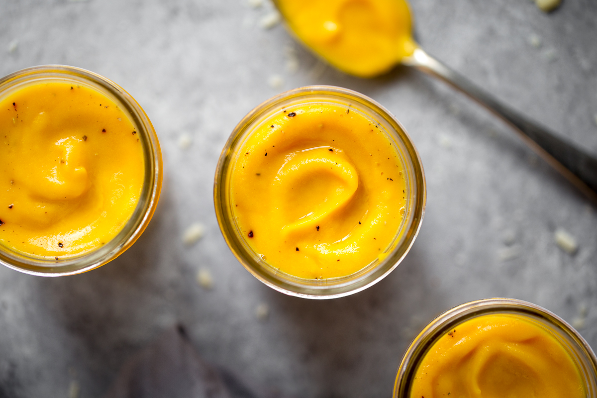 overhead closeup of butternut squash sauce in jar with spoon in the background