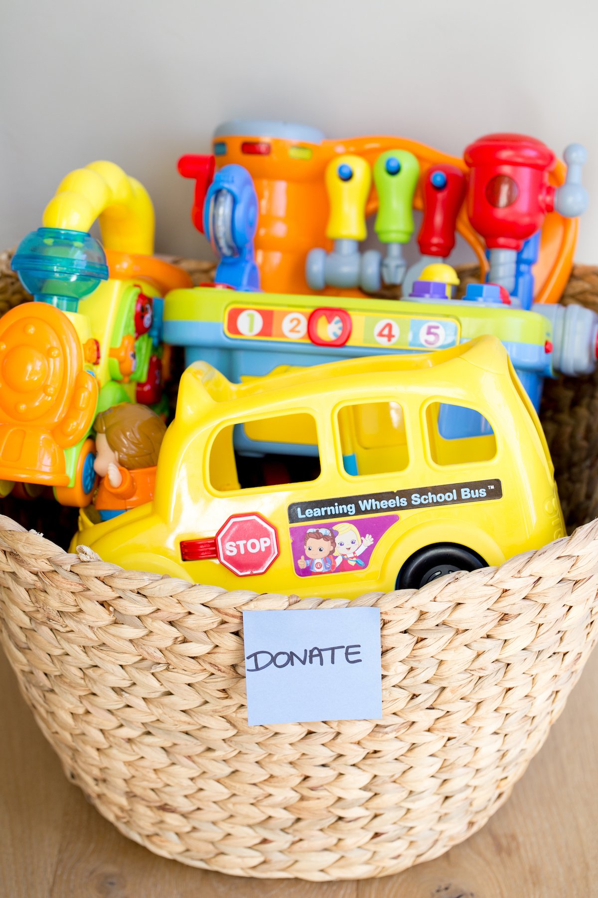 closeup of plastic toys in a woven basket with a "donate" sticker on it