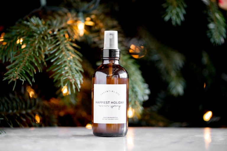 bottle of homemade essential oil holiday room spray with a lit tree in the background title text overlay
