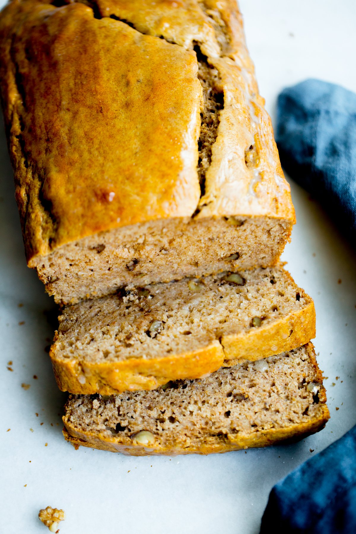 close up photo of a loaf of healthy banana bread with walnuts on marble background with a blue napkin