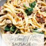 plate of linguine with sun dried tomato spinach and sausage in a grey bowl on white marble background with title text overlay