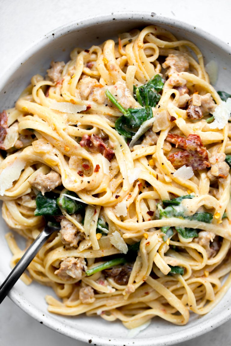 overhead shot of a bowl of instant pot sausage and sun-dried tomato linguine pasta on a white background