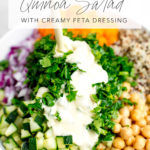 mediterranean quinoa salad ingredients with creamy feta dressing being poured on top with title text overlay