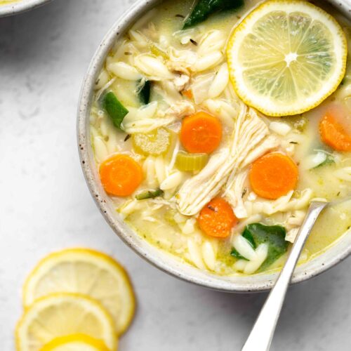 overhead photo of a bowl of instant pot lemon chicken soup with orzo on a light background