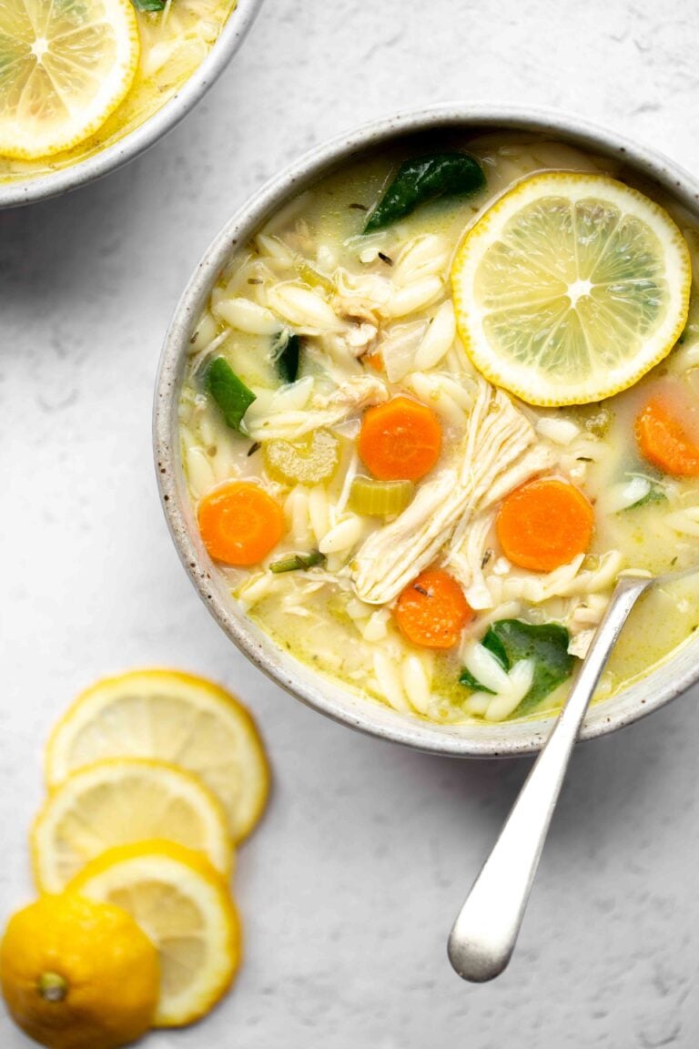 overhead photo of a bowl of instant pot lemon chicken soup with orzo on a light background