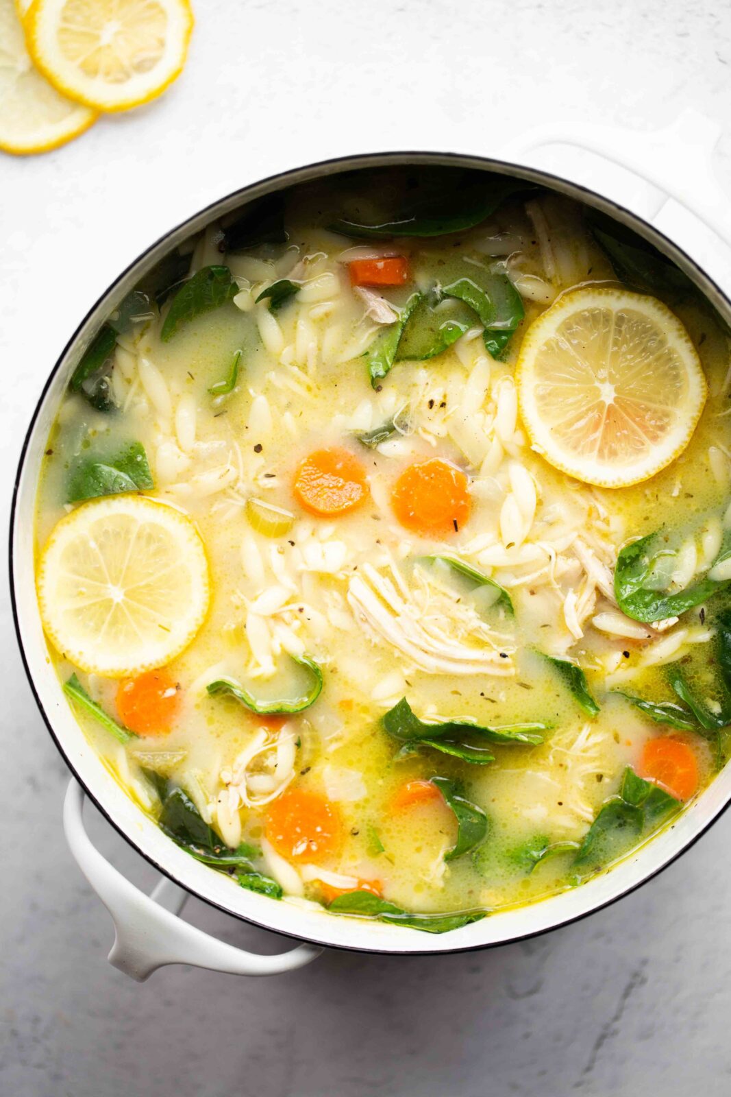 overhead photo of a pot of instant pot lemon chicken soup with orzo on a light background
