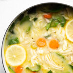 beautiful overhead photo of a pot of instant pot lemon chicken soup with orzo on a light background with title text overlay