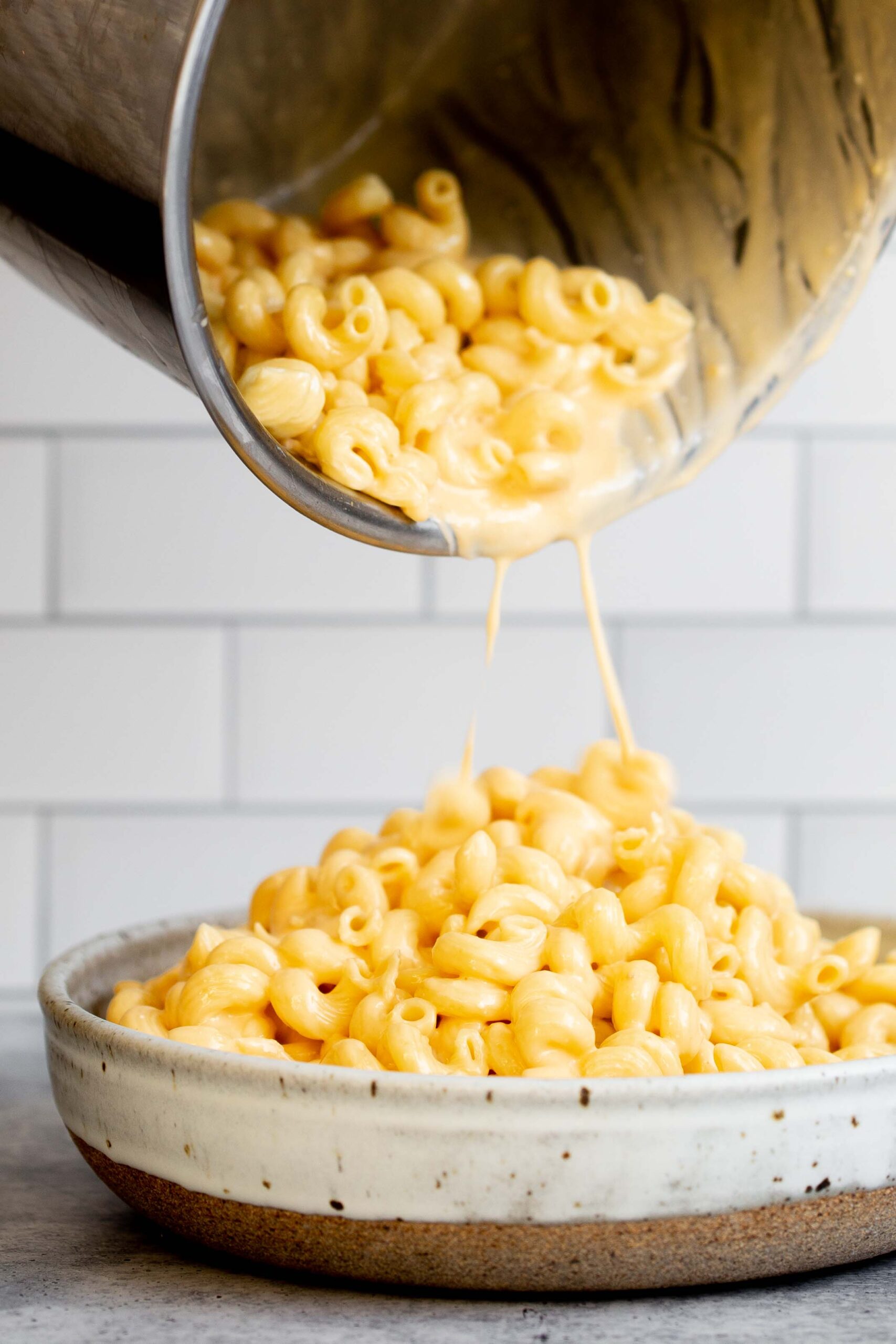 Instant Pot mac and cheese recipe with pasta being poured from pot into serving bowl