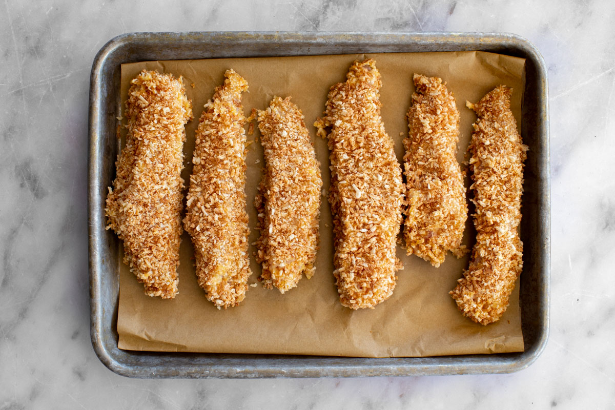 Raw chicken tenders on a baking sheet to freeze