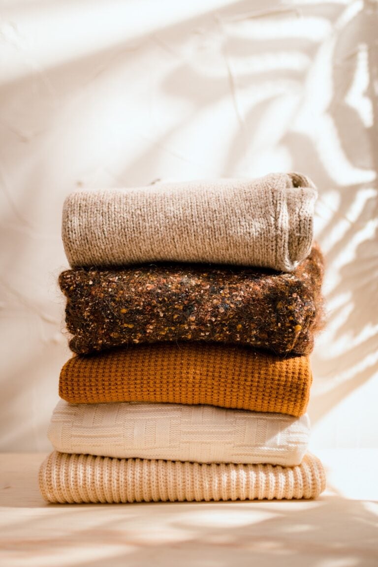 Fall sweaters stacked on a textured background
